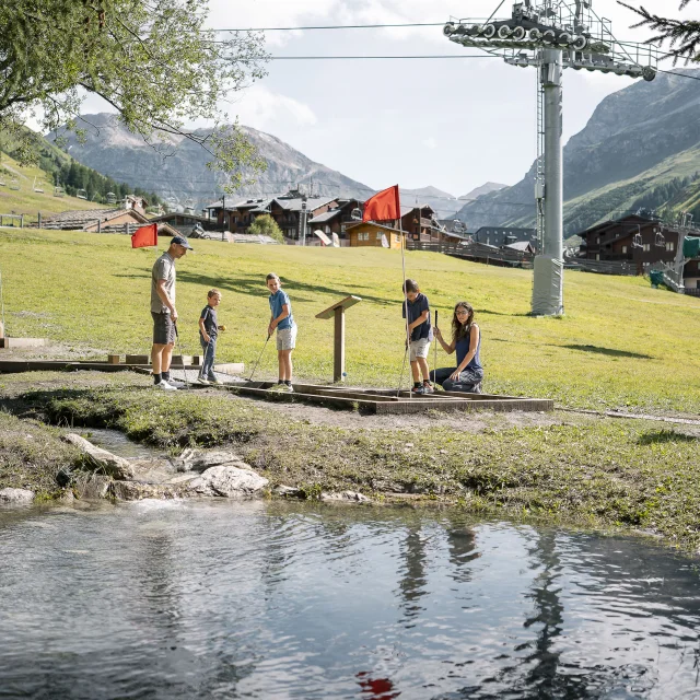 Mini golf en famille (parents et enfant) sur le front de verdure en été à Val d'Isère