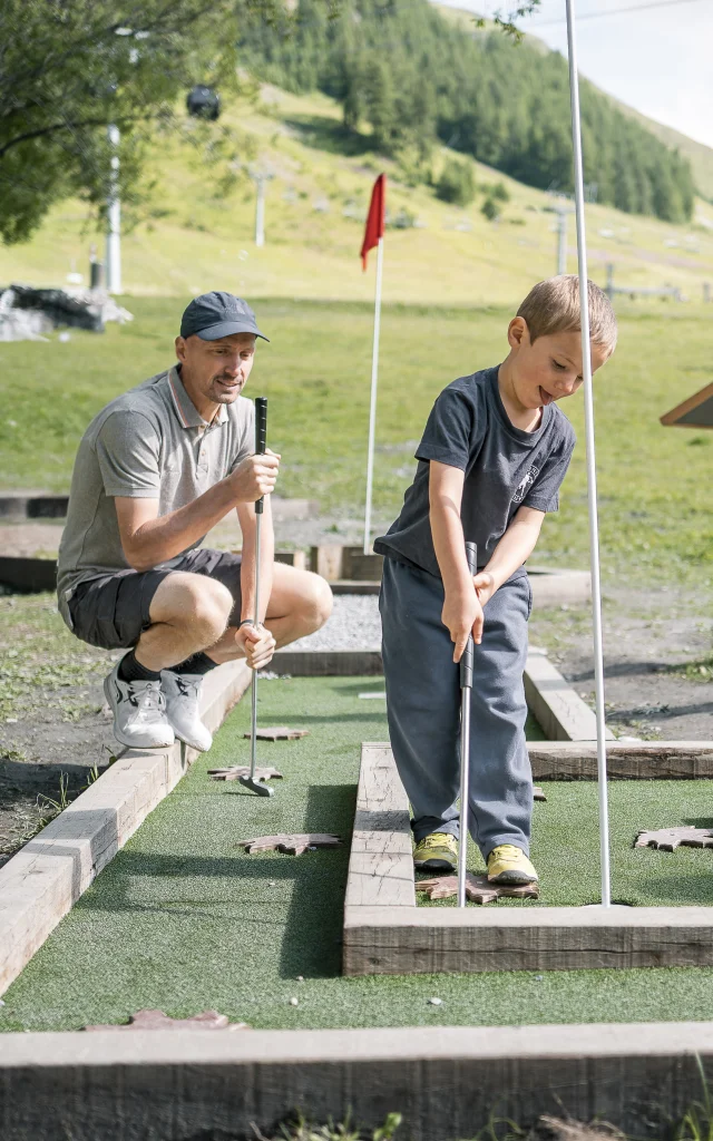 Mini golf en famille (parents et enfant) sur le front de verdure en été à Val d'Isère