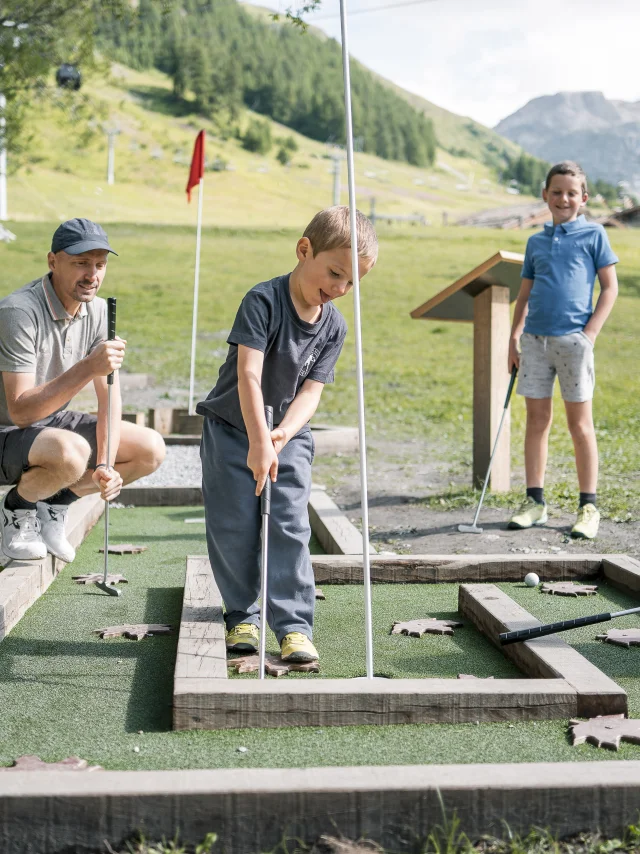 Mini golf en famille (parents et enfant) sur le front de verdure en été à Val d'Isère