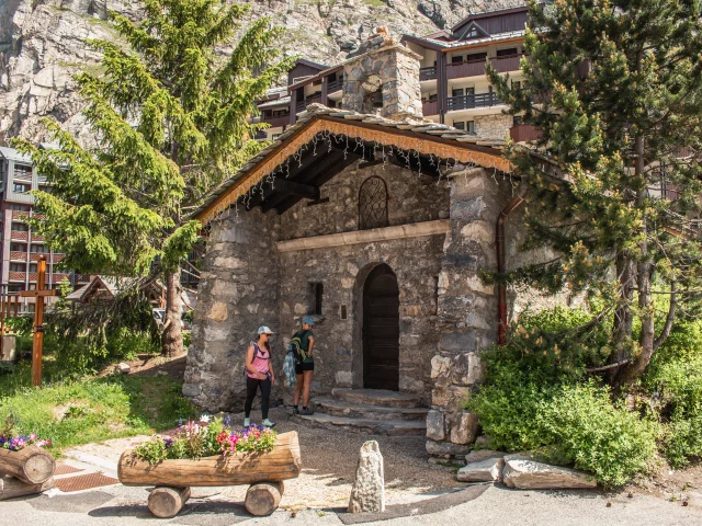 Friends strolling past the Saint-Germain de La Daille chapel in Val d'Isère in summer