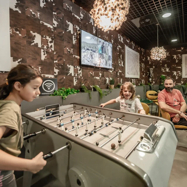 Enfants qui jouent au babyfoot dans l'espace Lounge du Centre Aquasportif