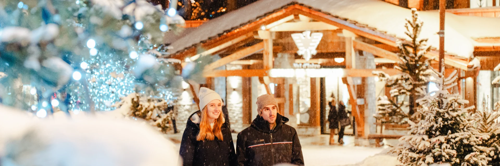 Couple sous la neige devant l'Office de Tourisme