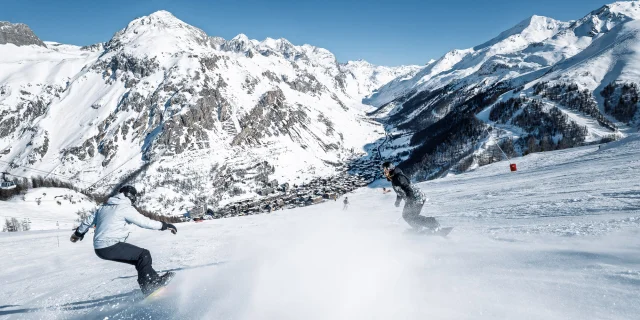 Snowboardeurs avec vue sur le village sur les pistes de Val d'Isère