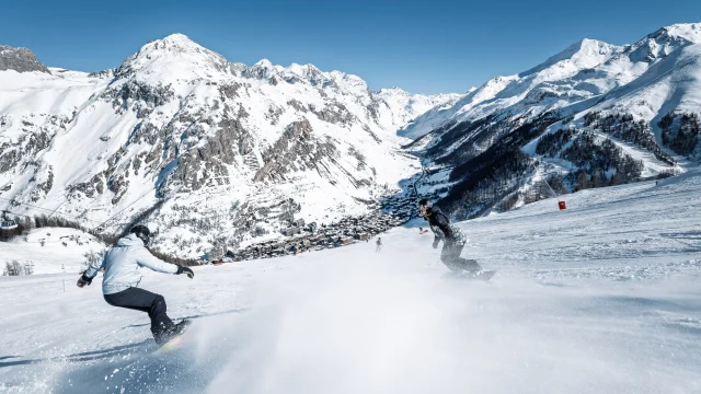Snowboardeurs avec vue sur le village sur les pistes de Val d'Isère