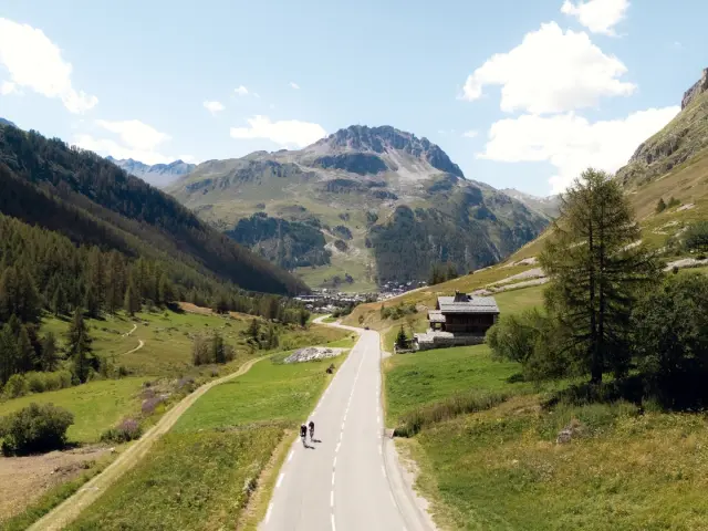 Cyclistes sur la route du Col de l'Iseran après Le Fornet avec vue sur le rocher de Bellevarde