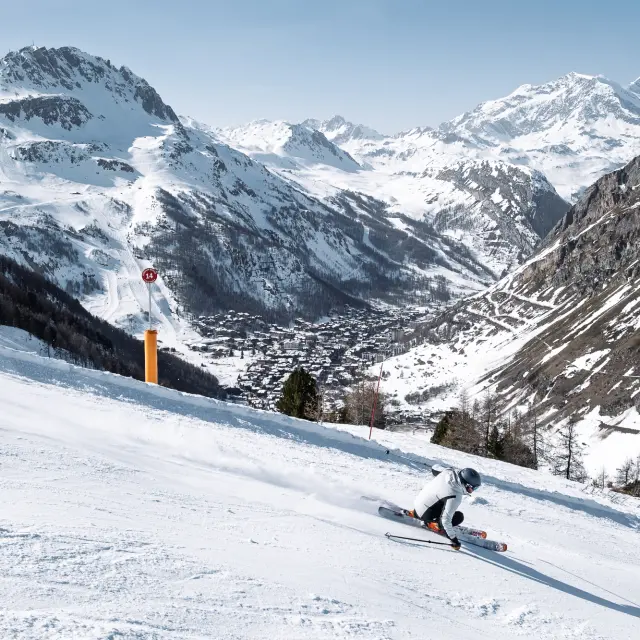 Un skieur sur la piste avec en fond le village
