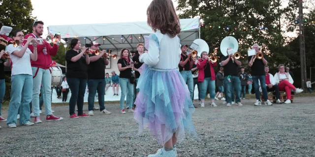 Petite fille de dos au premier plan au milieu de musiciens