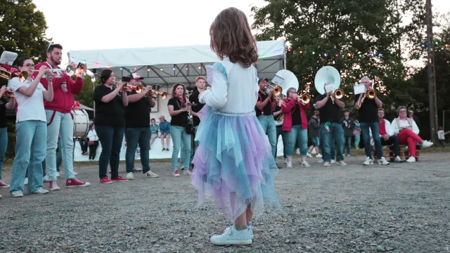 Petite fille de dos au premier plan au milieu de musiciens
