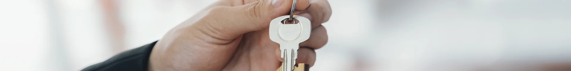Real estate agent holding key with house shaped keychain.  Real estate, buy or sale or moving home or renting property. Mortgage and business concept.