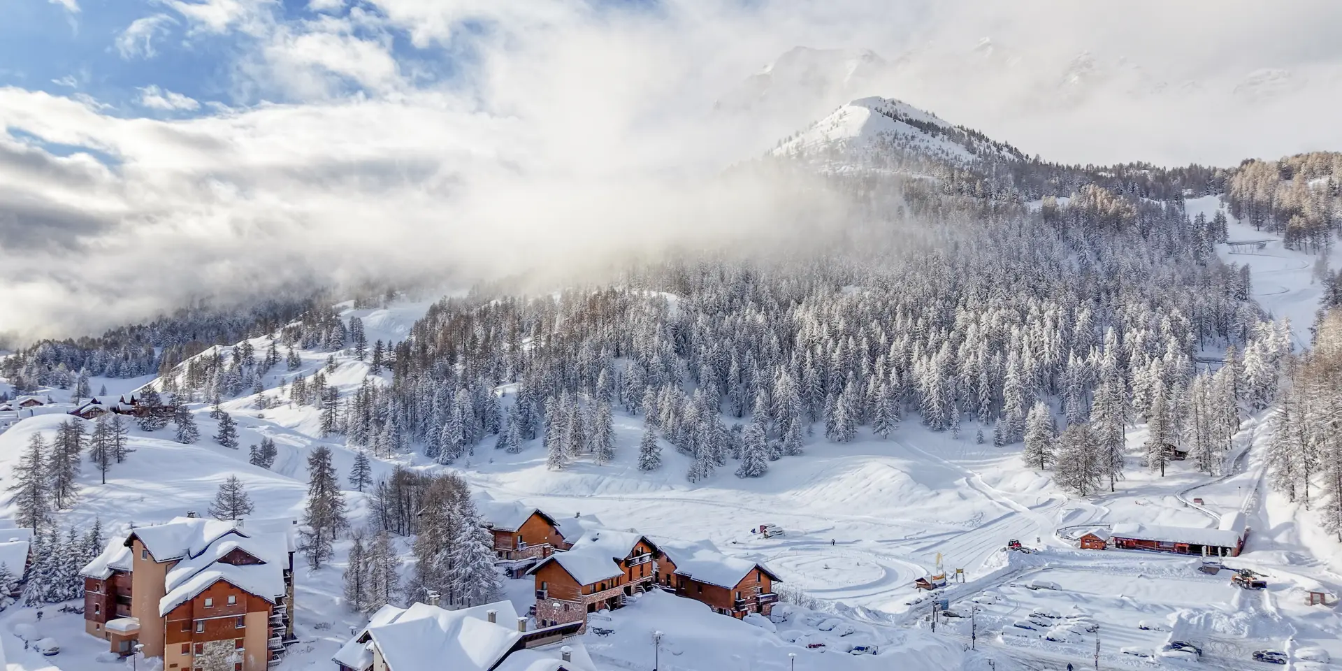 Chute de neige à Vars, vue sur les village en drone avec les mélèzes enneigés.