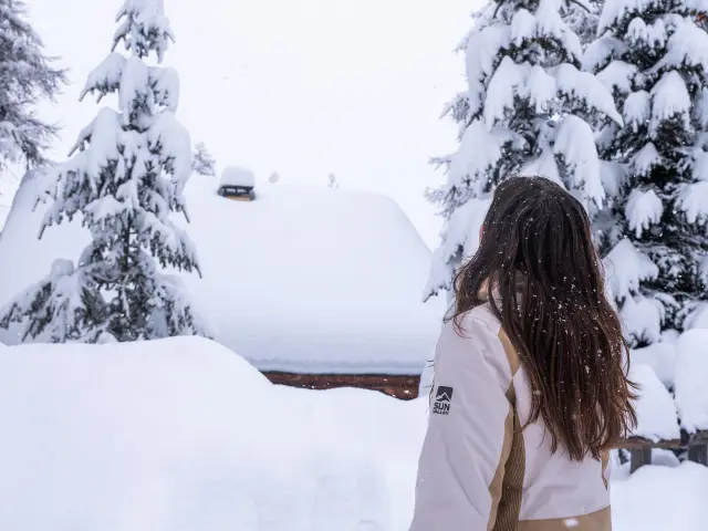 Femme sous la neige à Vars en train de regarder les mélèzes avec une épaisse couche de neige