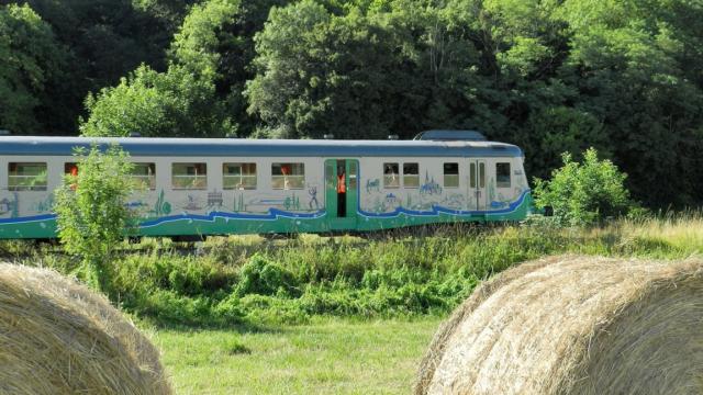 Train touristique avec en premier plan des bottes de paille à la campagne à Thoré-la-Rochette