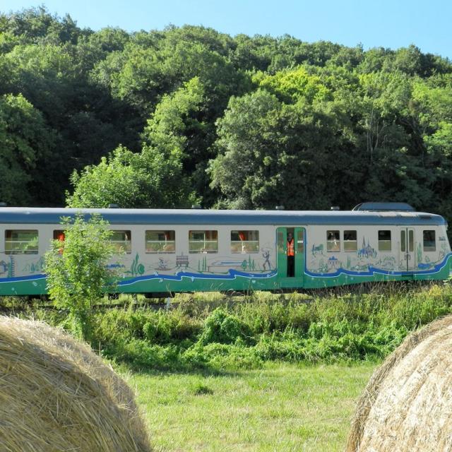 Train touristique avec en premier plan des bottes de paille à la campagne à Thoré-la-Rochette