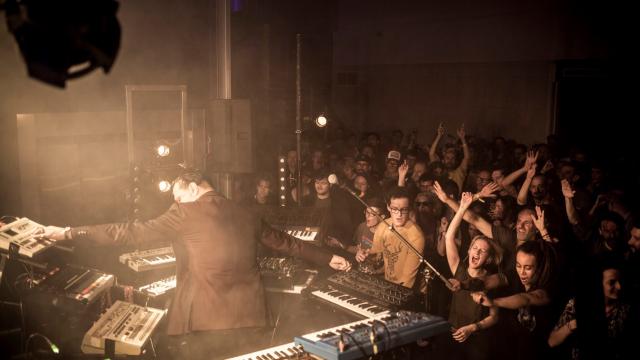 Concert : spectateurs devant un musicien avec plusieurs synthé