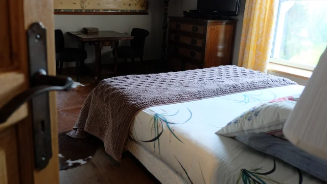 Vue sur une porte de chambre avec vue sur le lit et meubles en fond