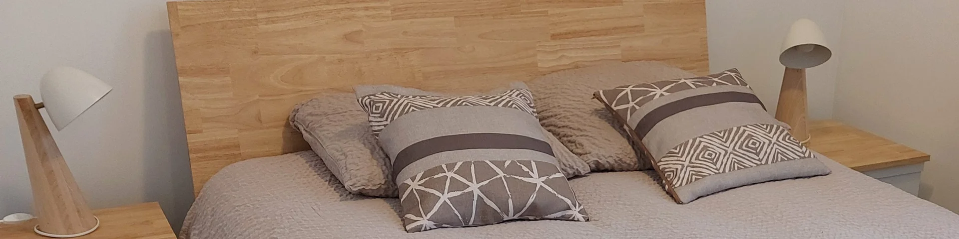 Chambre avec lit draps beiges marron avec arbre sur le mur