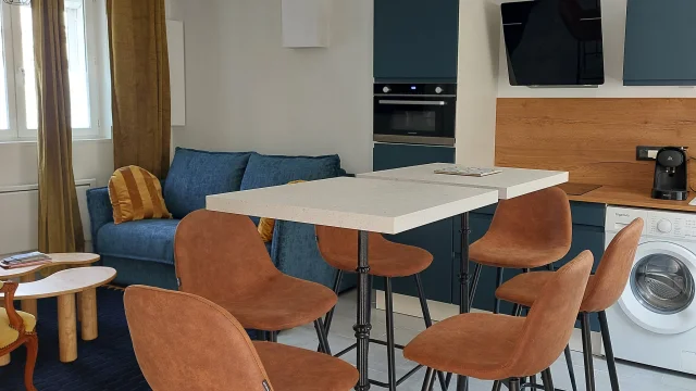 Salle à manger avec able blanche, chaises, marrons, cuisine aménagée et salon