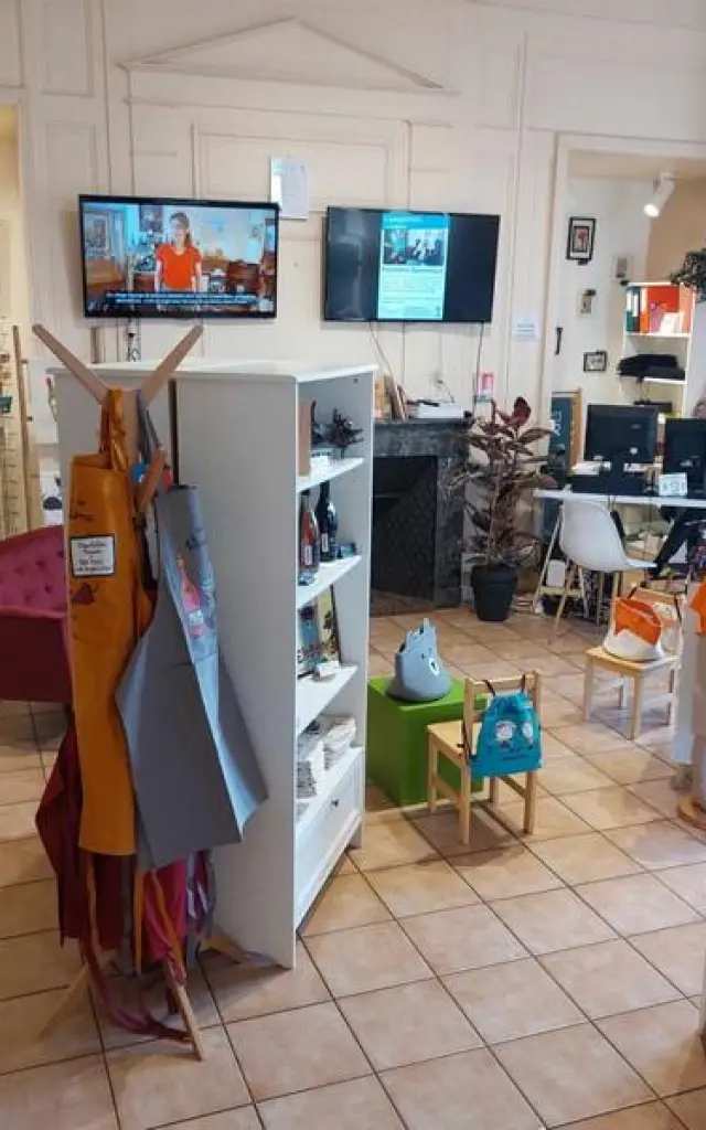 Vue d'ensemble d'une pièce avec meubles et produits à vendre, au fond deux télévisions accrochées au mur