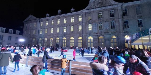 Patinoire avec patineurs de nuit devant un grand bâtiment