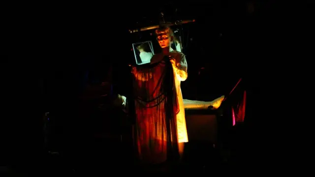 Femme dans le noir avec drapé orangé devant elle