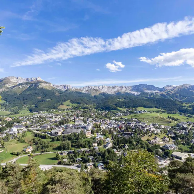Village entouré de montagnes avec des maisons et des champs verts