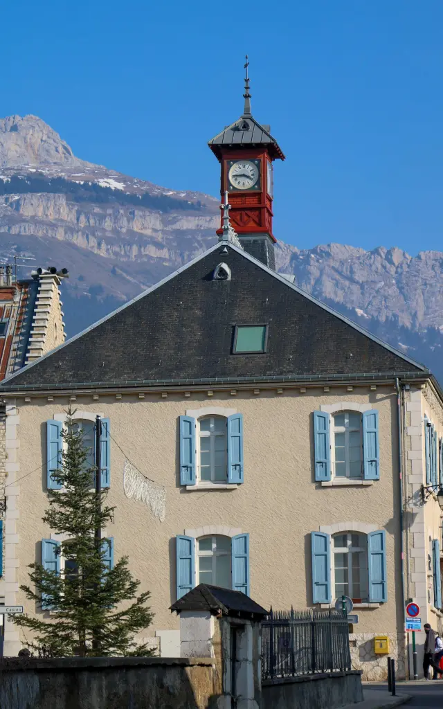 Maison avec horloge et montagnes enneigées en arrière-plan