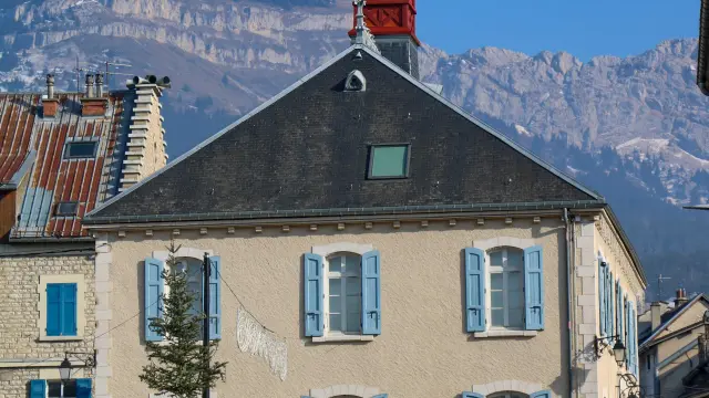 Maison avec horloge et montagnes enneigées en arrière-plan