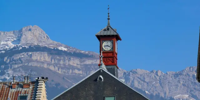 Casa con orologio e montagne innevate sullo sfondo