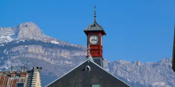 Casa con orologio e montagne innevate sullo sfondo