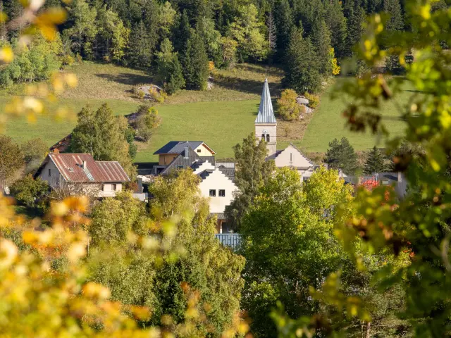 Village avec une église et des maisons entourées de verdure