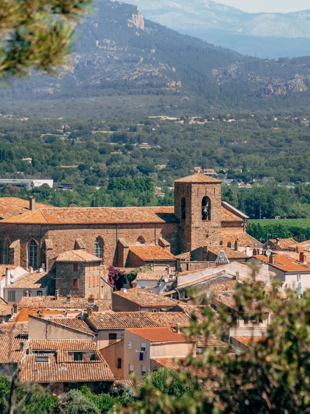 Vue panoramique du village médiéval de Roquebrune-sur-Argens avec l'église Saint-Pierre-Saint-Paul et les paysages du Var en arrière-plan.