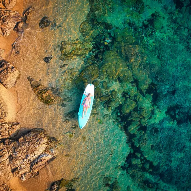 Vue aérienne d'une personne en paddle dans les eaux cristallines des Issambres sur la Côte d'Azur à Roquebrune-sur-Argens.